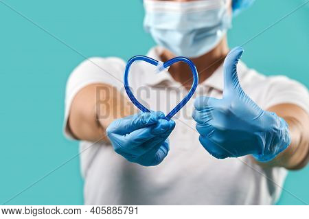 Closeup Of Dentist Hands Holding A Saliva Ejector In The Shape Of Heart And Showing Thumbs Up. Isola