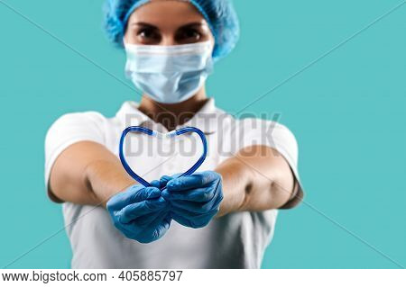 Close Up Of Saliva Ejector In The Shape Of Heart In The Female Dentist Hands Isolated On A Blue Back