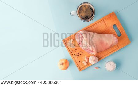 Raw Pork Knuckle, Stout And Other Ingredients For Cooking Baked Pork Knuckle In Beer On Blue Backgro