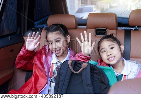 Two Happy Students Raising Hands And Motion While Enjoying Road Trip In Car. Sisters Smiling And Loo