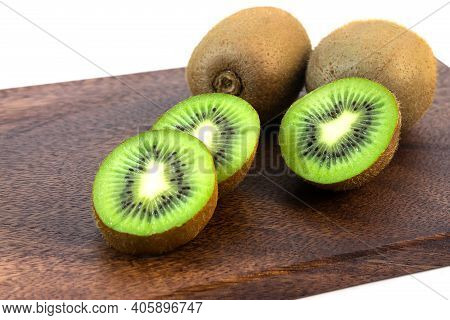 Fresh Wholesome Ripe Kiwi Fruit Whole Or In Pieces On A Wooden Kitchen Board.