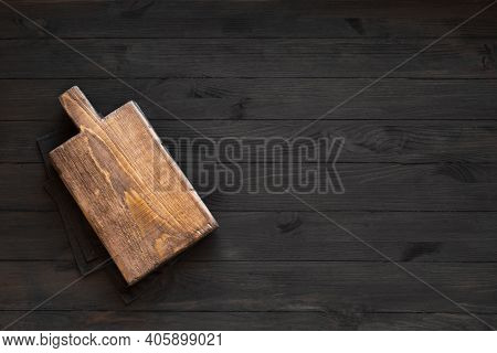 Empty Wooden Board On Black Wooden Kitchen Table, Top View, Copy Space. Wooden Platter, Copy Space.