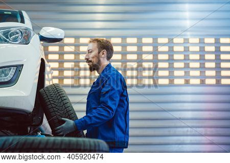 Car mechanic changing tire in his workshop lifting the wheel