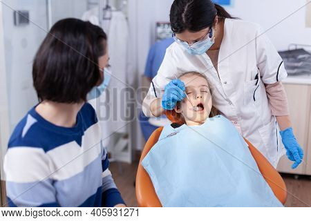 Young Stomatolog Using Curved Mirror To Check Dentistry Specialist During Child Cavity Consultation 