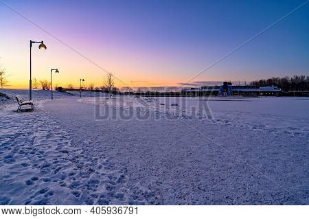 Sunrise Over Path In Park Covered In Snow