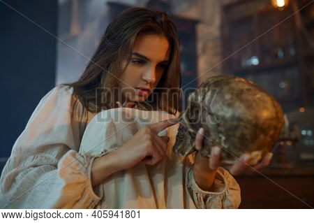 Scary demonic woman holds human skull, exorcism