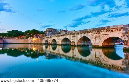 Rimini with Bridge of Tiberius at dusk, Emilia-Romagna, Italy. Landscape with water reflection. Italian architecture