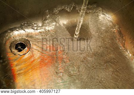 Water Splashing Down The Sink On Stainless Kitchen Sink. Scene Water Splashing Pouring Strong Of Wat