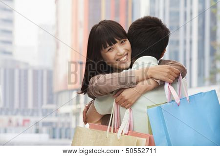 Young couple embracing with shopping bags, outdoors, Beijing