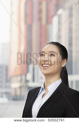 Portrait of smiling young businesswoman, looking up