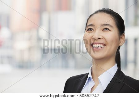 Close-up Portrait of smiling young businesswoman, looking up