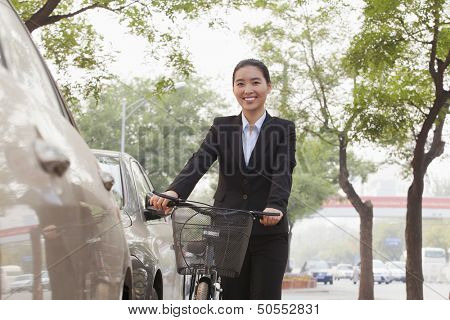 Young businesswoman holding a bicycle on the street, Beijing