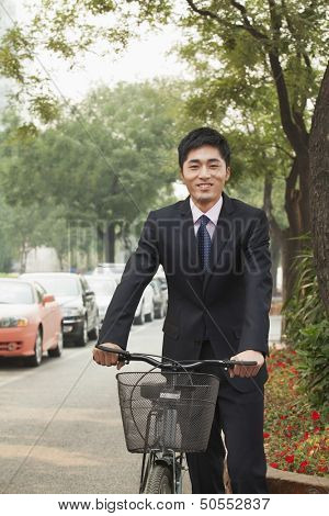 Young businessman holding a bicycle on a city street in Beijing