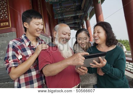 Chinese Family Looking At Digital Tablet In Jing Shan Park