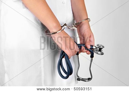 Doctor with stethoscope in handcuffs isolated on white