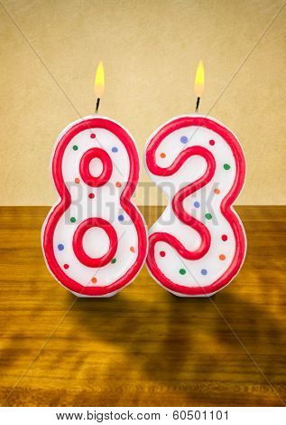 Burning birthday candles number 83 on a wooden background