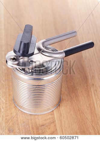 Can piercer with canned on wooden background