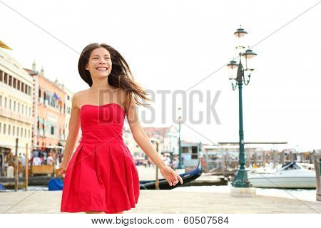Woman happy running in summer dress, Venice, Italy. Girl smiling laughing joyful having fun by water in Venice. Beautiful multiracial Asian Caucasian young woman cheerful and vivacious.