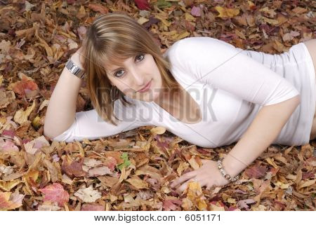 Giovane donna sdraiata In foglie di autunno