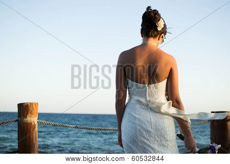 A new bride staring into the ocean.