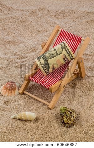 deck chair with dollars on the sandy beach. symbolic photo for travel costs, holidays, vacations. save on holiday