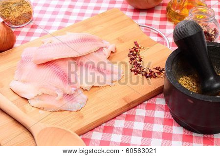 Raw fish tilapia on cutting board and spices