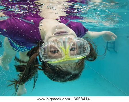 little girl having fun and swimming upside down underwater