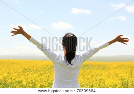 Cheering woman open arms at cole flower field