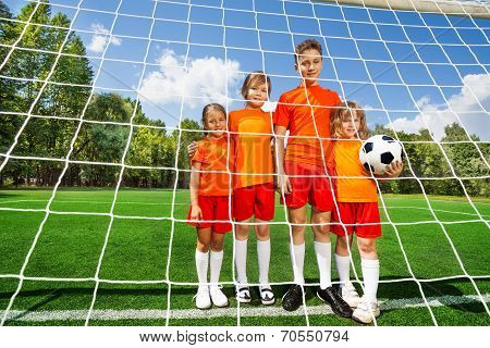 Different height kids stand in line with football