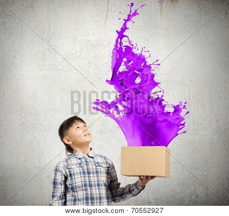 Young boy splashing colorful paint from carton box