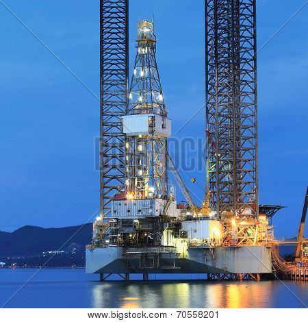 Jack up oil drilling rig in the shipyard for maintenance at sunset time