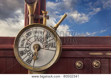 engine controls (telegraph) on a vintage ship bridge with a stormy sky in background