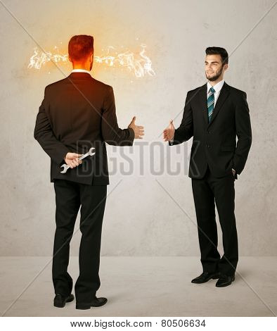Angry businessman hiding a weapon behind his back 