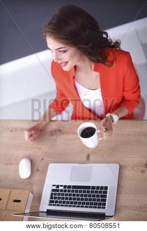 Attractive woman sitting at desk in office, working with laptop