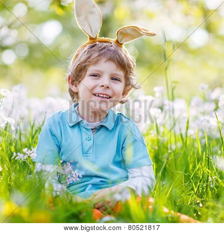 Cute Happy Little Kid Wearing Easter Bunny Ears At Spring Green Grass