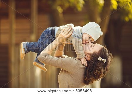 Mother with little daughter in her arms, playing in the yard.