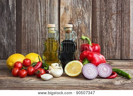 Olive Oil, Balsamic Vineger And Vegetables On Wooden Background