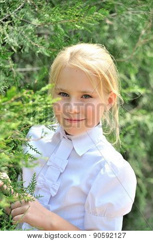 Portrait of the beautiful little girl in a park near thuyas