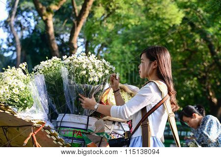 Young girl buy daisy flower from vendor in a street in Hanoi