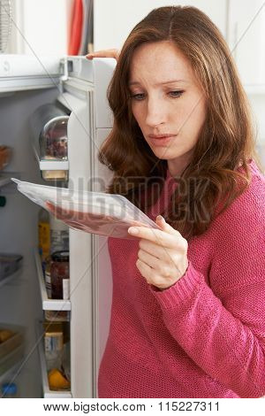 Concerned Woman Looking At Pre Packaged Meat