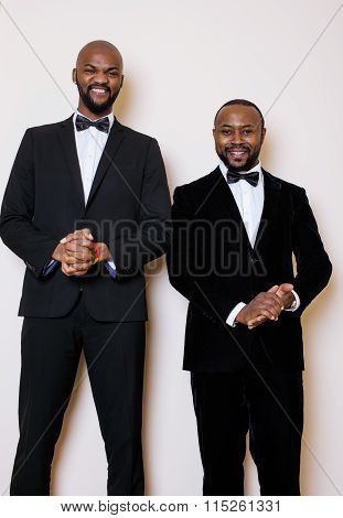 two afro-american businessmen in black suits emotional posing, gesturing, smiling. wearing bow-ties