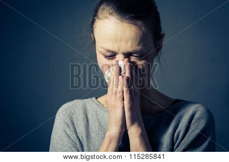 Young woman suffering from severe depression/anxiety/sadness, crying, tears coming from her eyes, blowing her nose