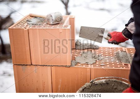 Construction Site Of New House During Winter, Man Working With Bricks And Cement, Building Walls