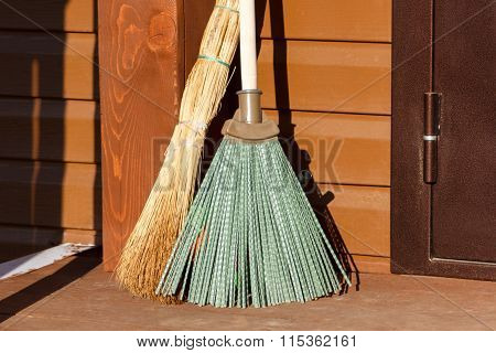 Broom And Besom Standing On Wooden Floor