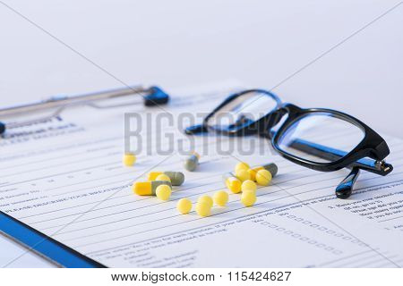 Pills and glasses on top of hospital form.