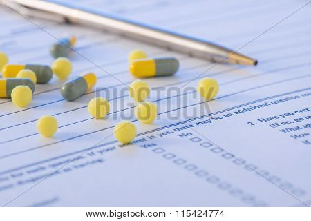 Pen and some medicines on top of hospital form.