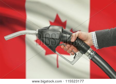Fuel Pump Nozzle In Hand With National Flag On Background - Canada