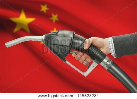 Fuel Pump Nozzle In Hand With National Flag On Background - China