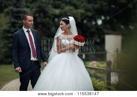 Newlywed Valentynes Posing In A Romantic European Park With Roses Bouquet