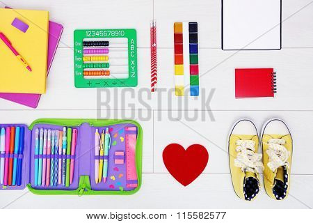 School set with heart, shoes and supplies on light wooden background